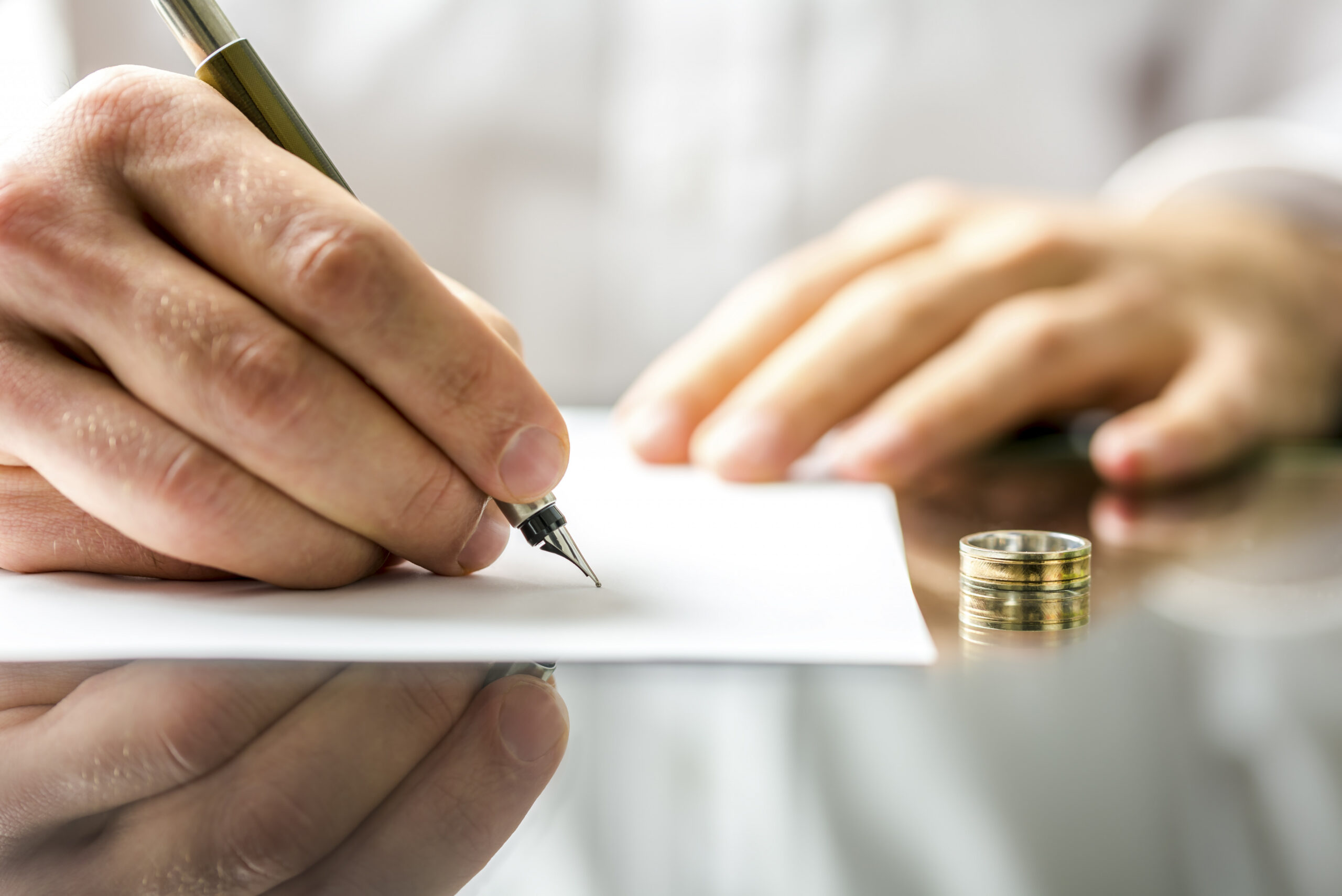 man writing on paper next to ring